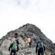Mountain climbers reaching the peak of a rocky mountain.