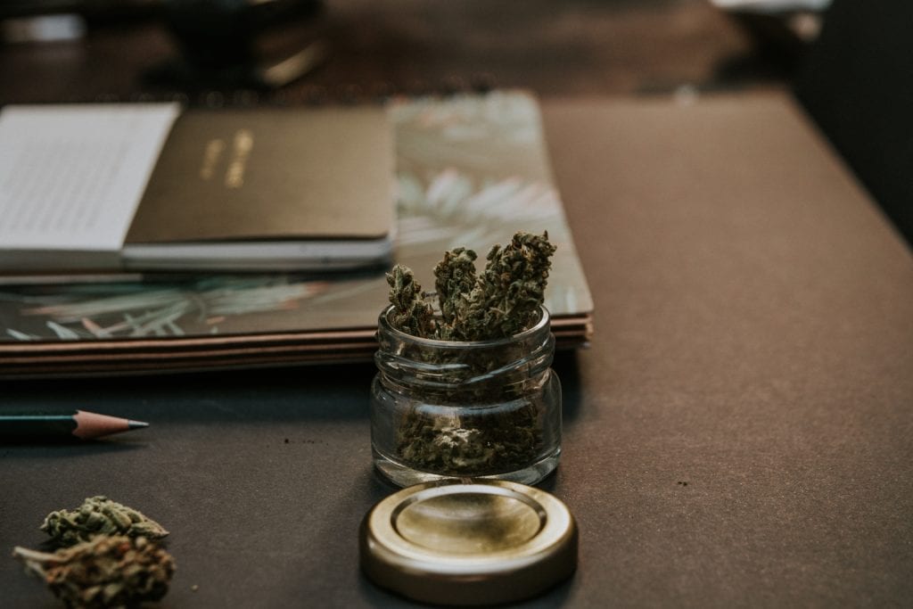 cannabis in jar next to notepads 